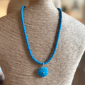 Blue beaded necklace on a mannequin bust with a blurred background